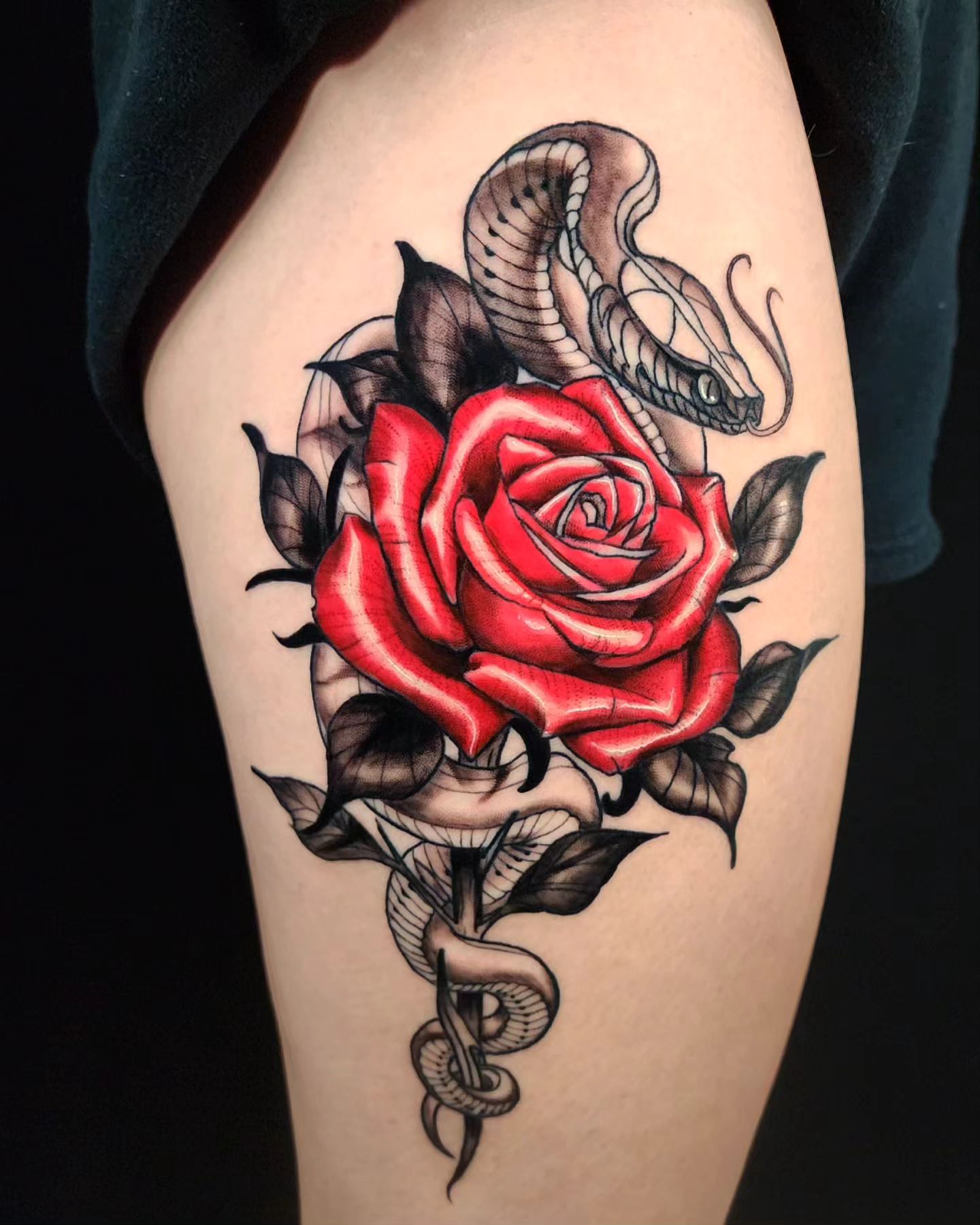 Nahaufnahme des roten Rosen- und Schlangen-Tattoos