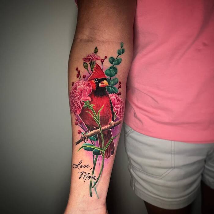 Watercolor tattoo of bird sitting on a perch surrounded by carnation flowers