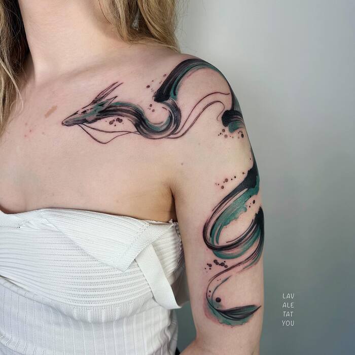 Watercolor tattoo of sea dragon framing the shoulder in black and green colors