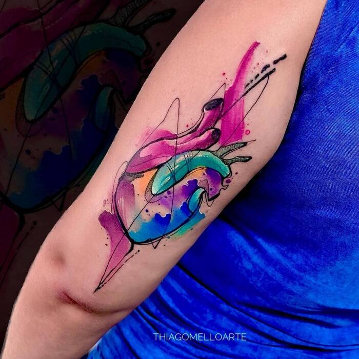 Watercolor tattoo of realistic heart image in pink, blue, purple and orange colors