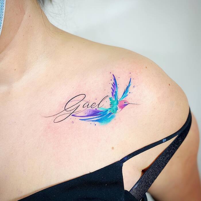 Watercolor tattoo of hummingbird in red, blue and purple colors with name over it