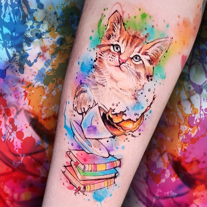 Watercolor tattoo of cat pouring a cup of coffee on the books