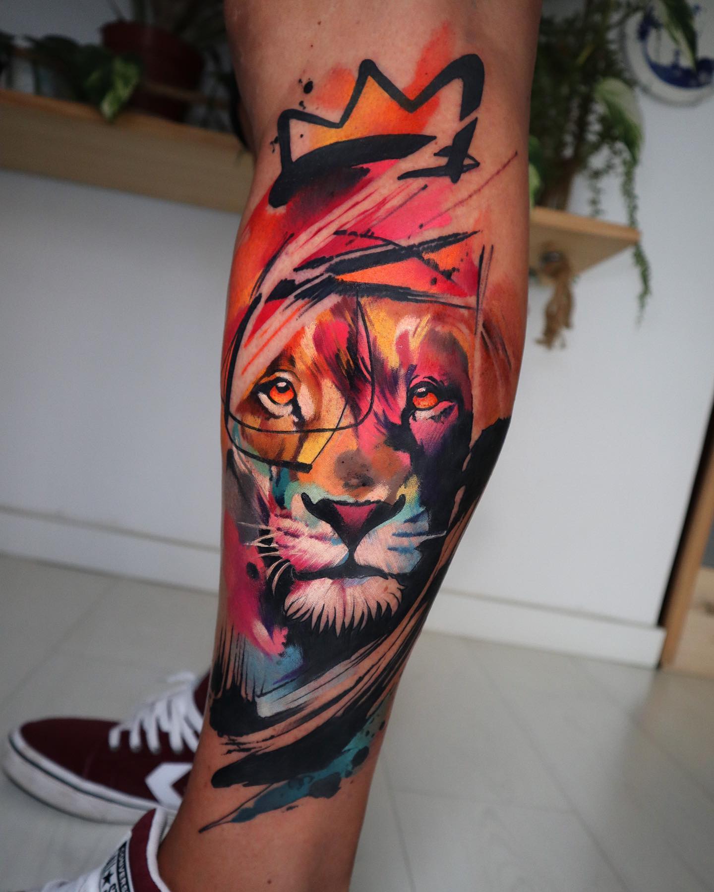 Akwarelowy tatuaż przedstawiający lwa z czarną koroną