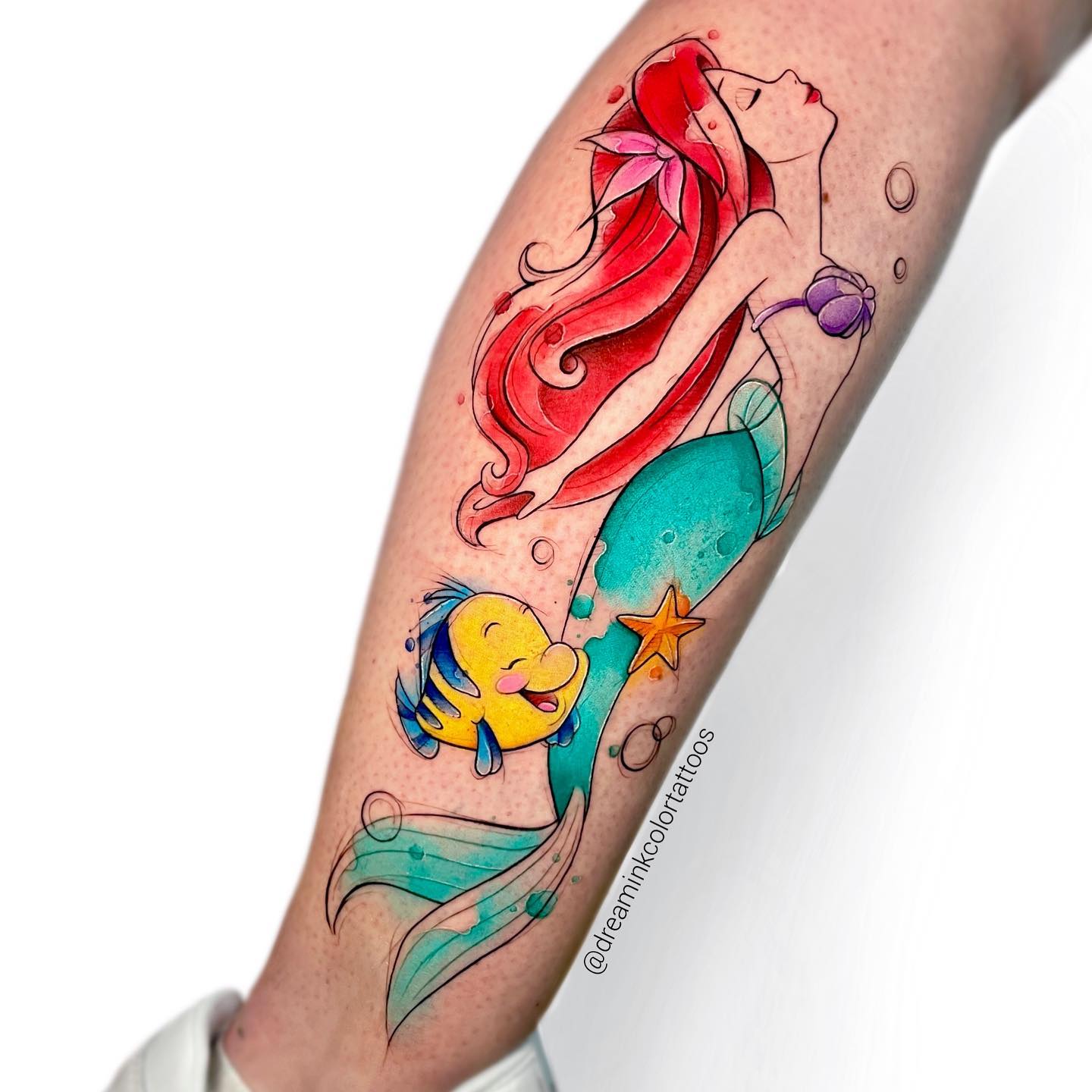 Akwarelowy tatuaż przedstawiający Ariel unoszącą się na powierzchni