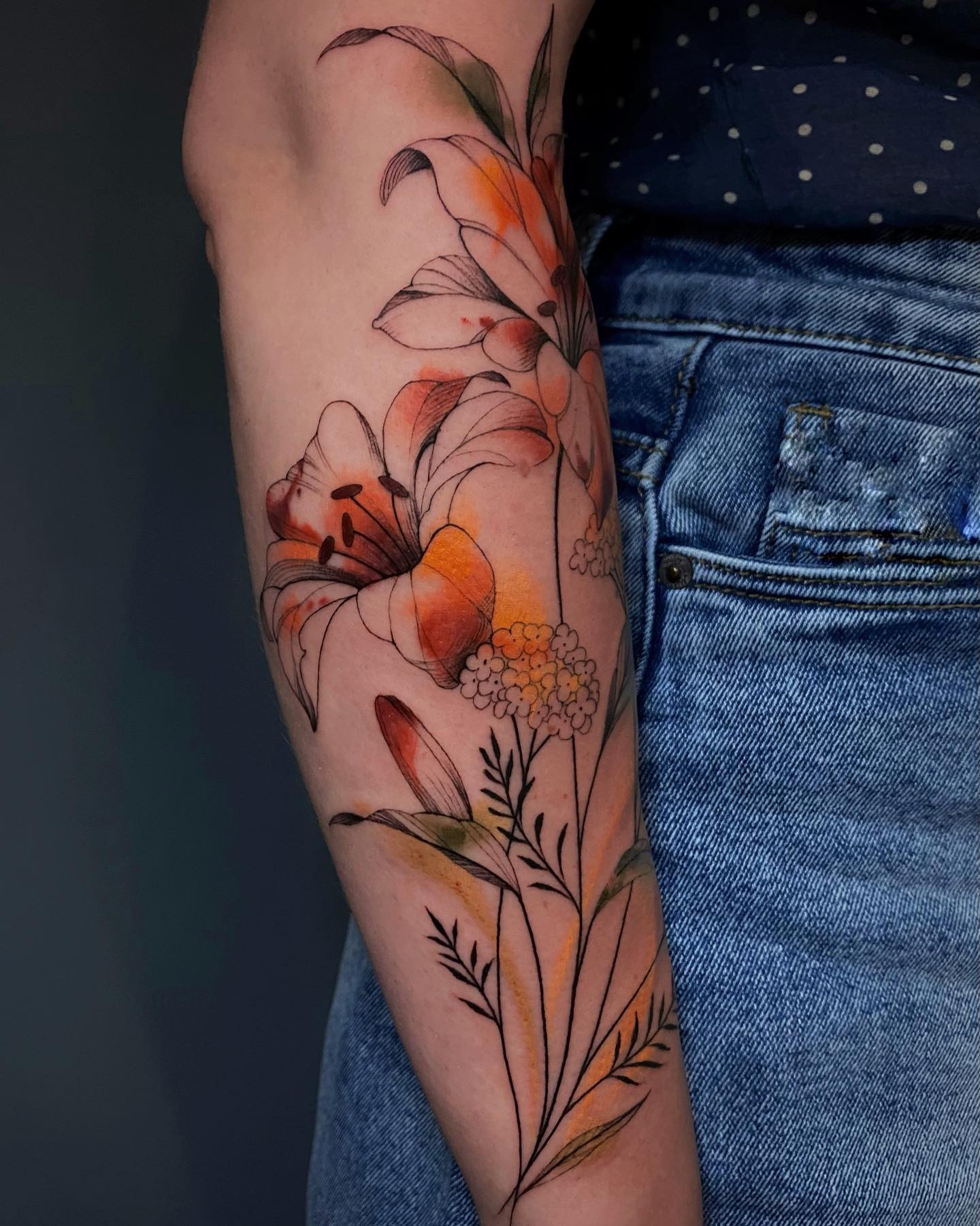 Akwarelowy tatuaż przedstawiający kwiat lilii w głównych kolorach czarnym, brązowym i pomarańczowym