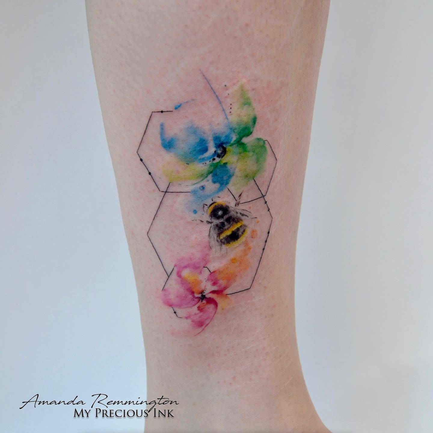 Akwarelowy tatuaż przedstawiający pszczołę siedzącą na czarnych cienkich plastrach miodu