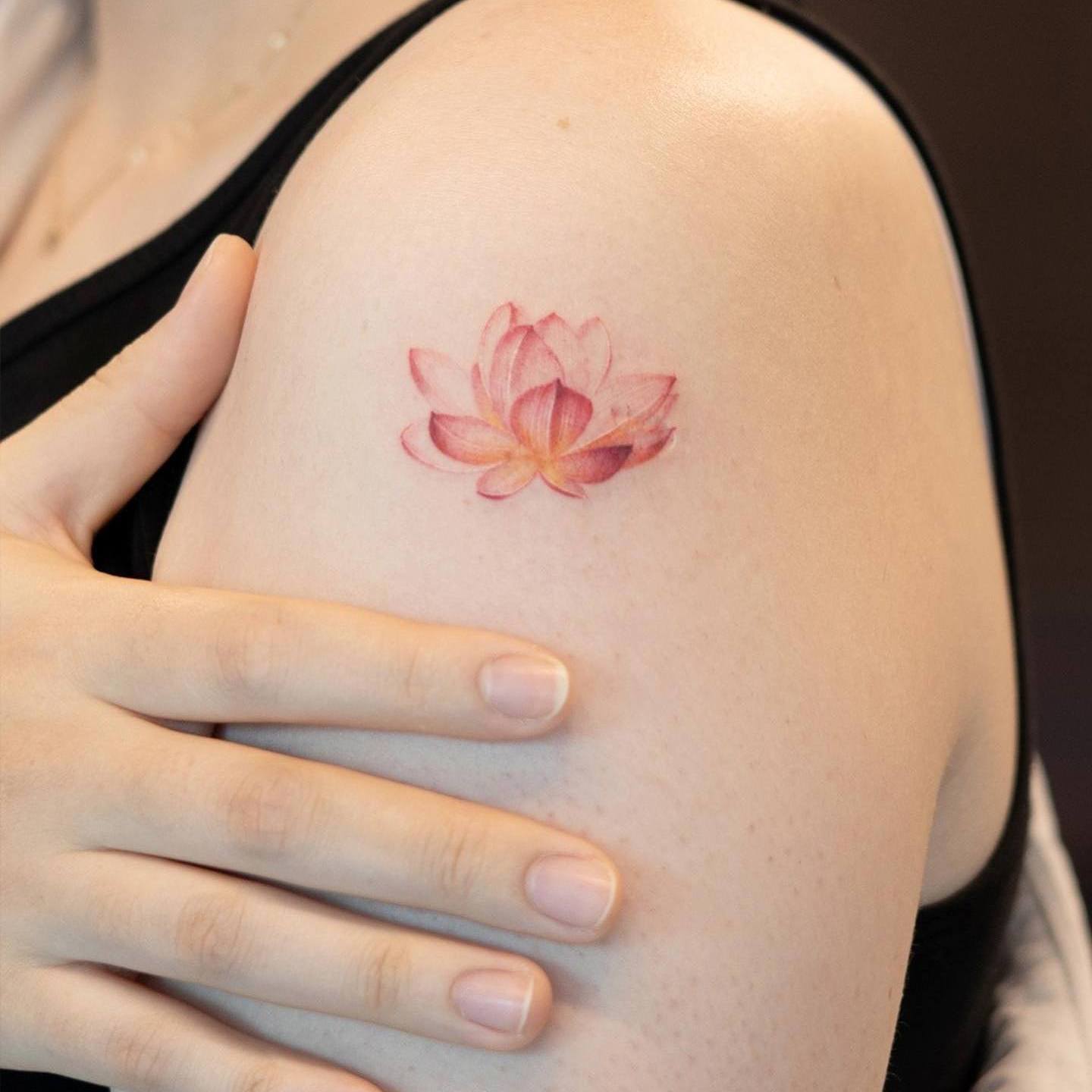 Akwarelowy tatuaż przedstawiający mały czerwony lotos wyglądający jak sylwetka