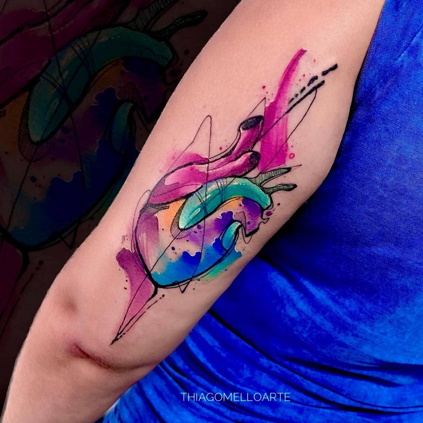 Akwarelowy tatuaż przedstawiający realistyczny obraz serca w kolorach różowym, niebieskim, fioletowym i pomarańczowym