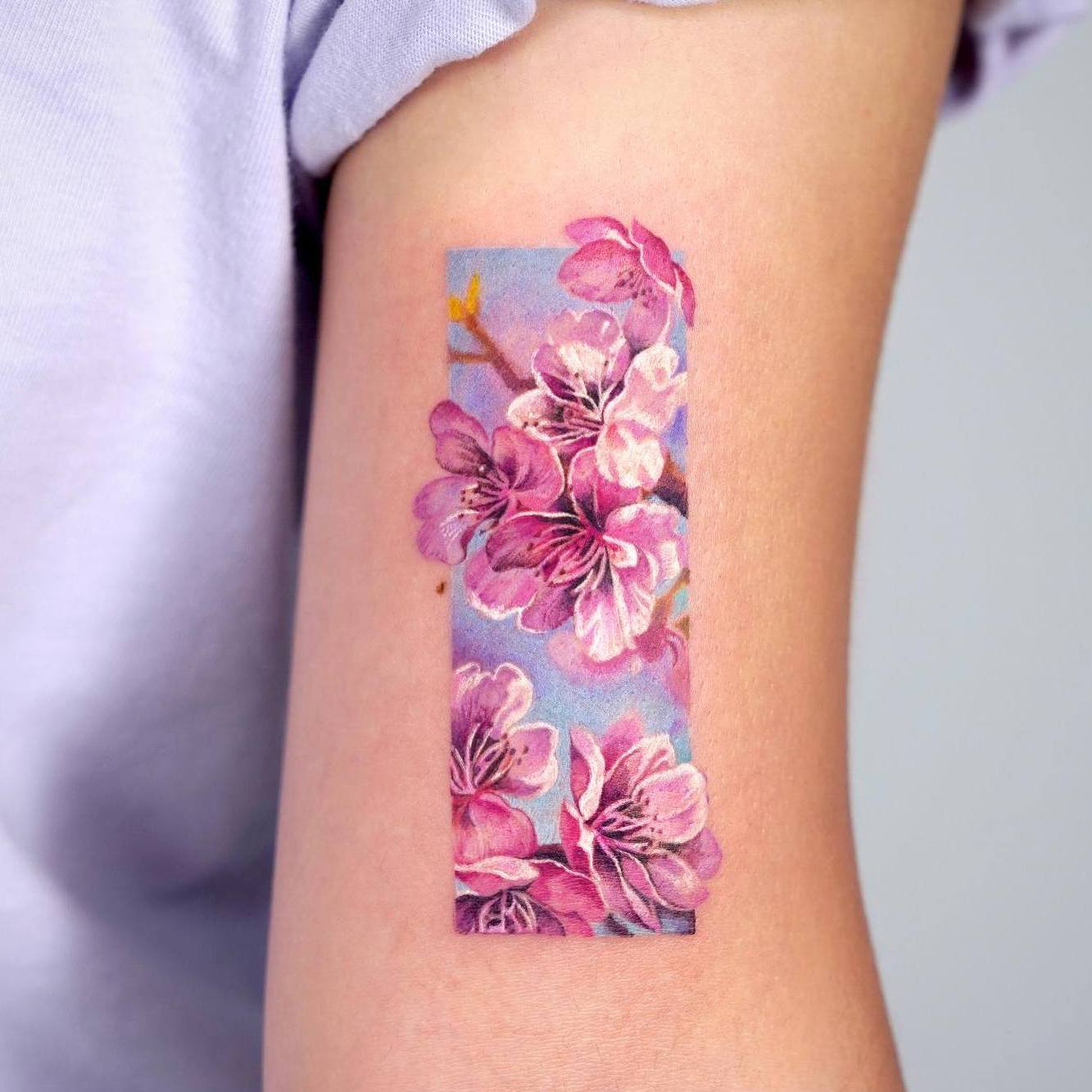 Akwarela tatuaż przedstawiający różowy kwiat wiśni na błękitnym tle