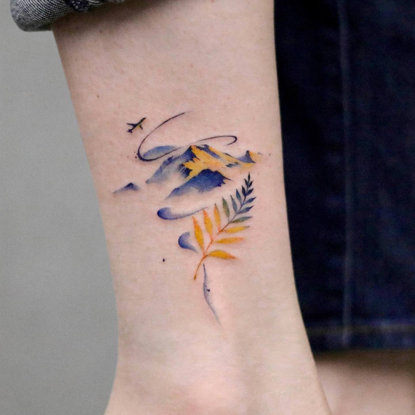 Akwarela tatuaż przedstawiający małe góry w kolorze niebieskim i żółtym