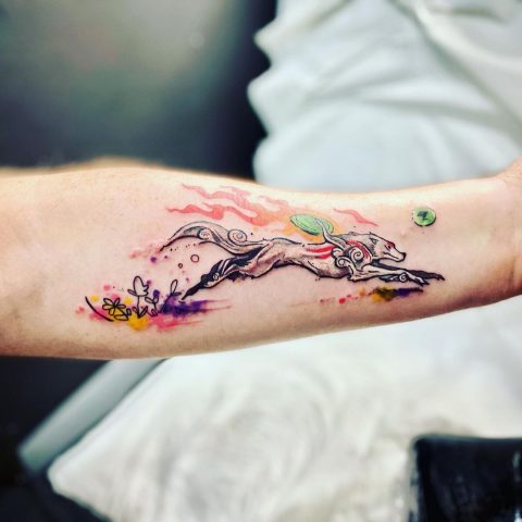 kolorowy tatuaż biegnącego wilka na ramieniu