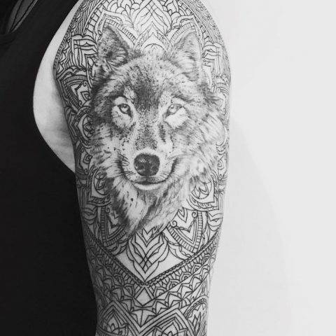 tatuaż z wilkiem mandalą na ramieniu